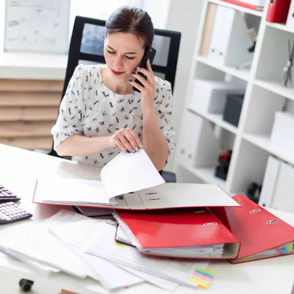 Tranmere Bookkeeping - working through financial records in a binder whilst on the phone