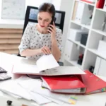 Tranmere Bookkeeping - working through financial records in a binder whilst on the phone