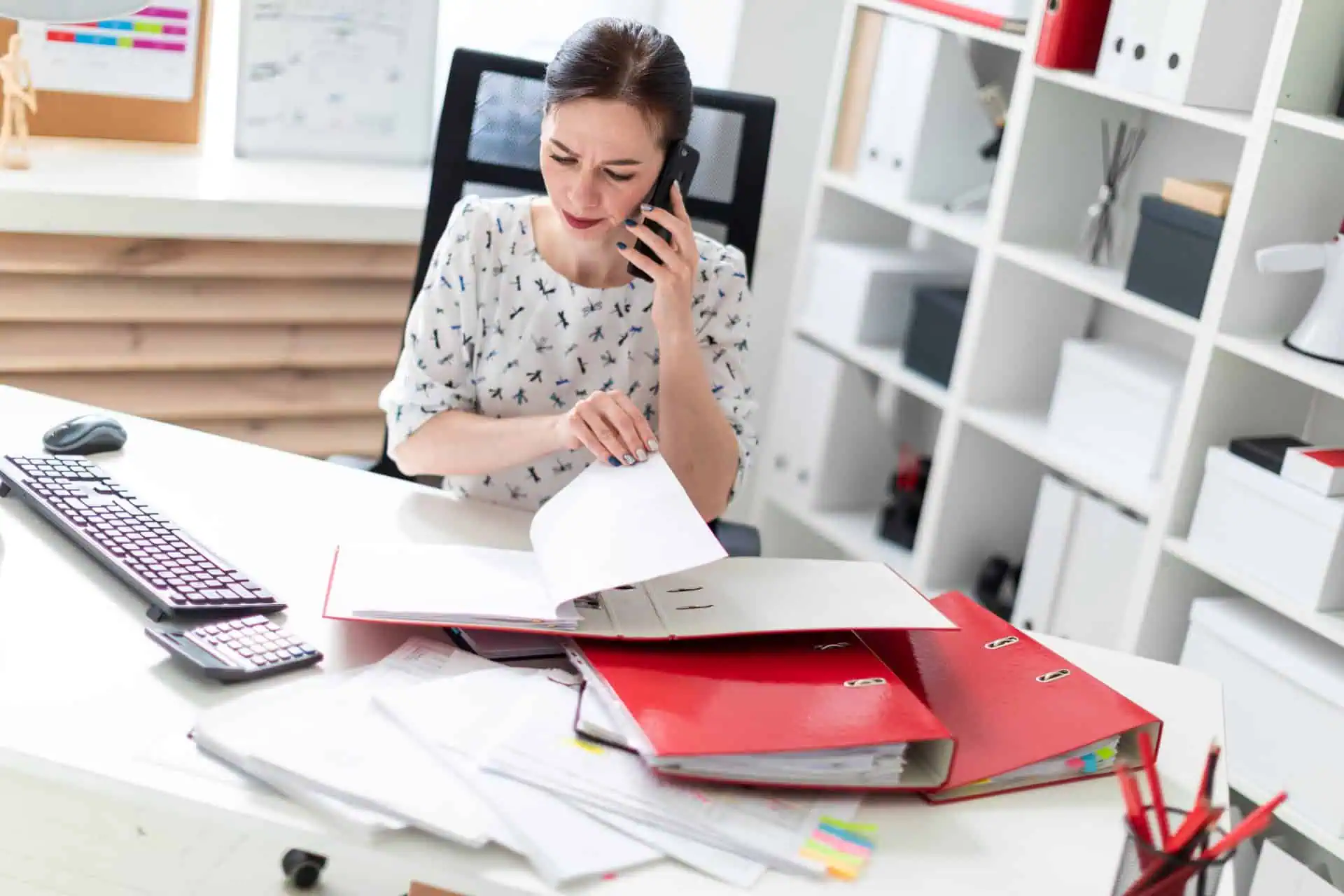 Tranmere Bookkeeping - working through financial records in a binder whilst on the phone